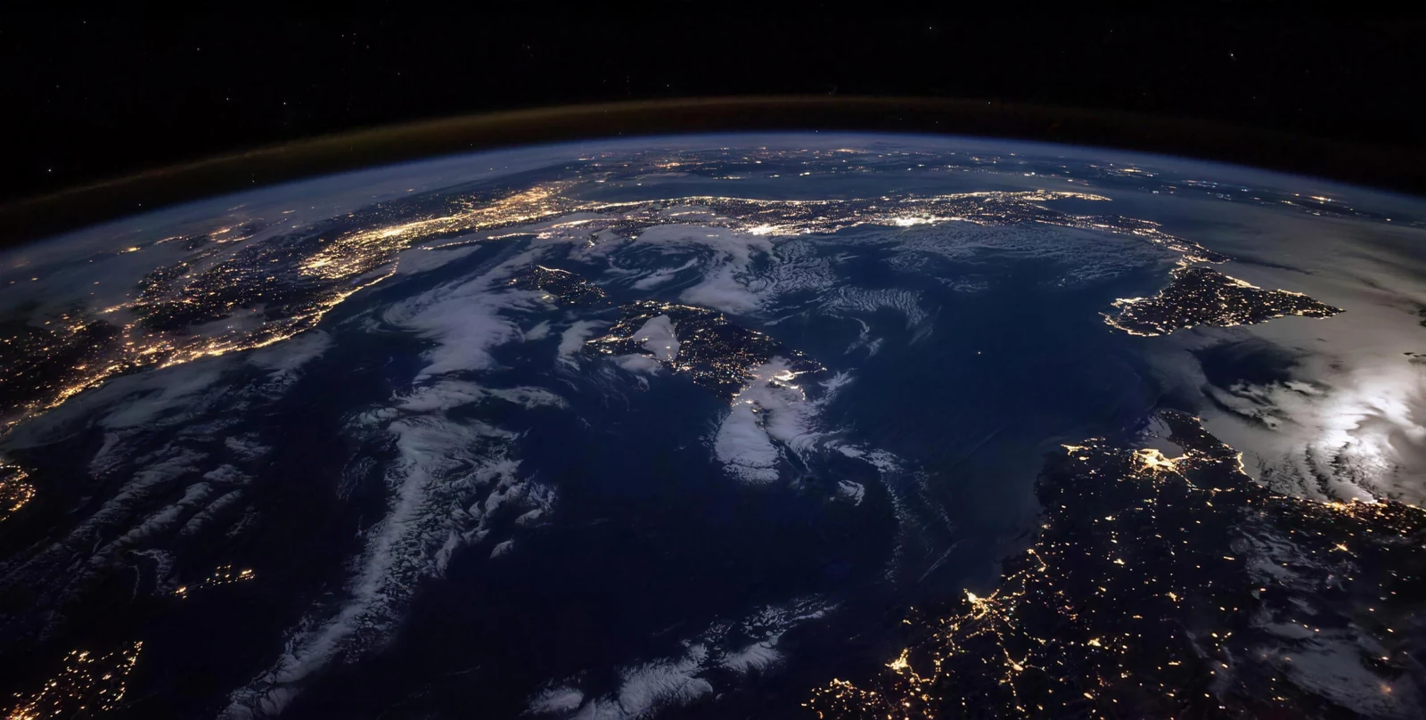 Night-side Earth from orbit with city lights tracing the continents